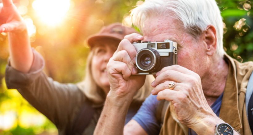 Senior trekker taking a photo with a film camera